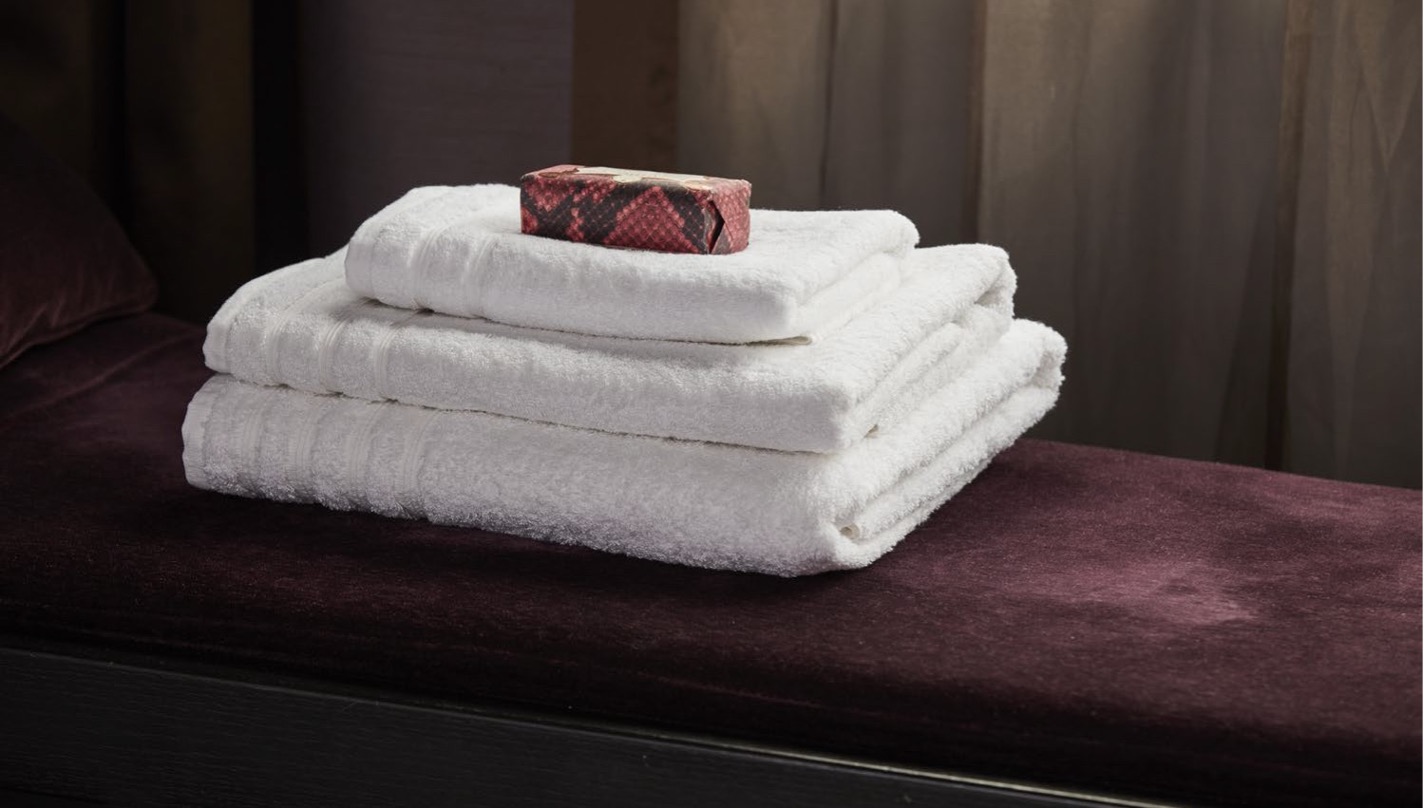 Clean white towels stacked with a small decorative towel on top.